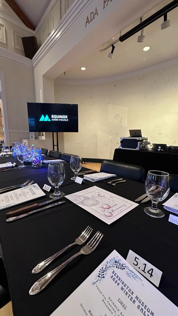 A place setting for the 2024 winter gala, with a monitor and the playback rack behind it.