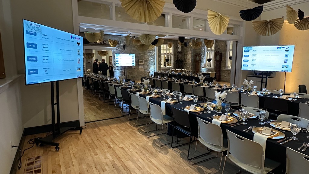Three 75-inch monitors around the dining room showing the Givergy silent auction.