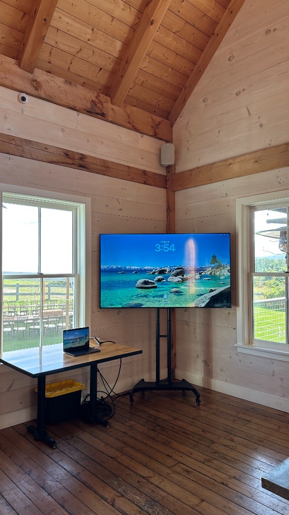 The same 75-inch playback setup in the pine room at Hill Farm Inn, looking toward the vaulted ceiling.