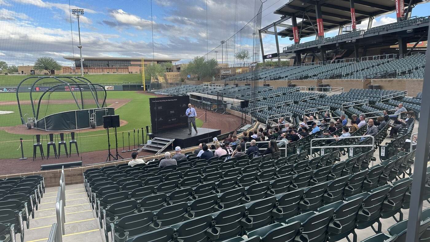 A speaker on the Salt River Fields stage, with the diamond and batting cage behind him.