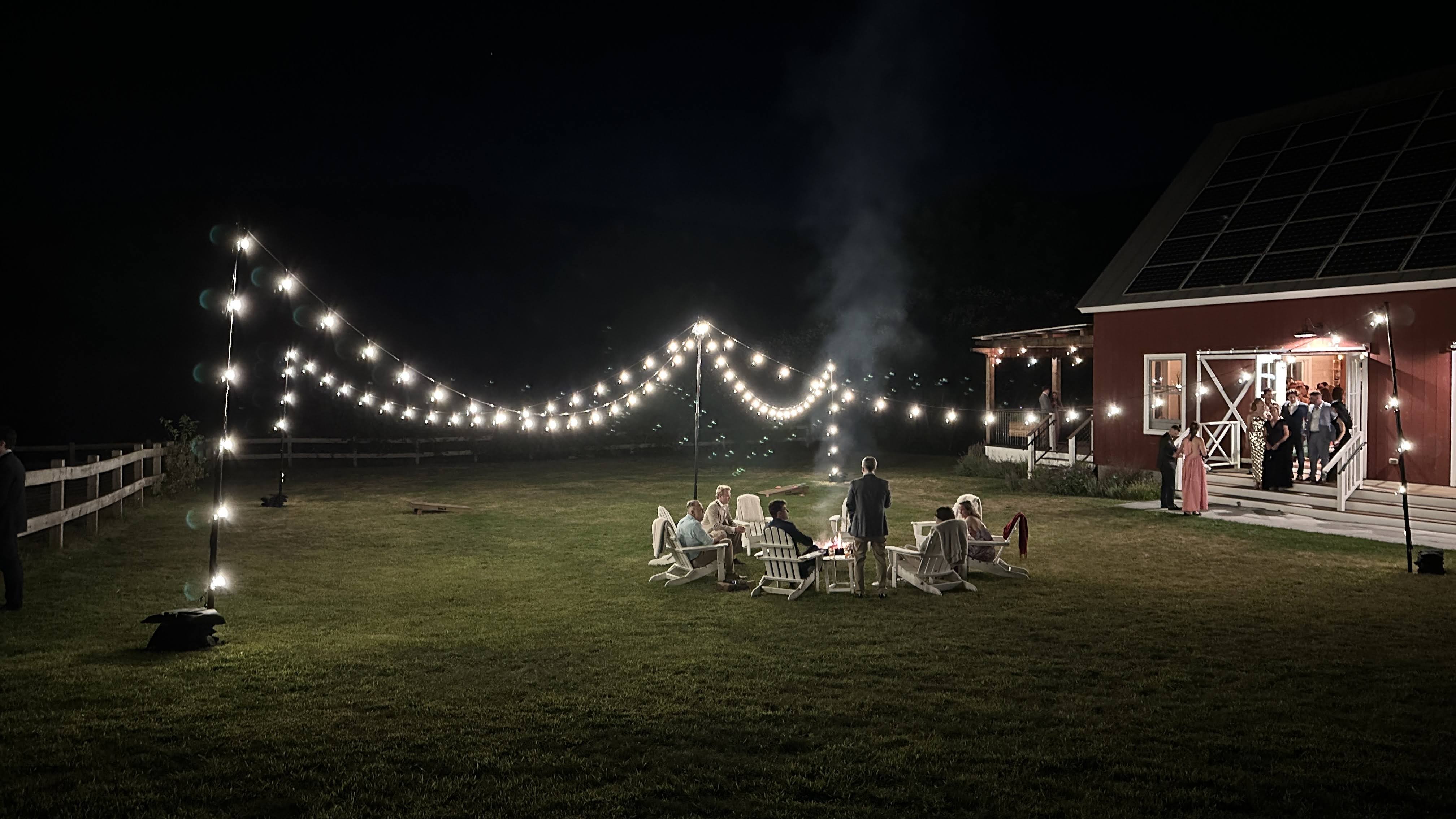 Evening atmosphere at Hill Farm with campfire and string light installation.