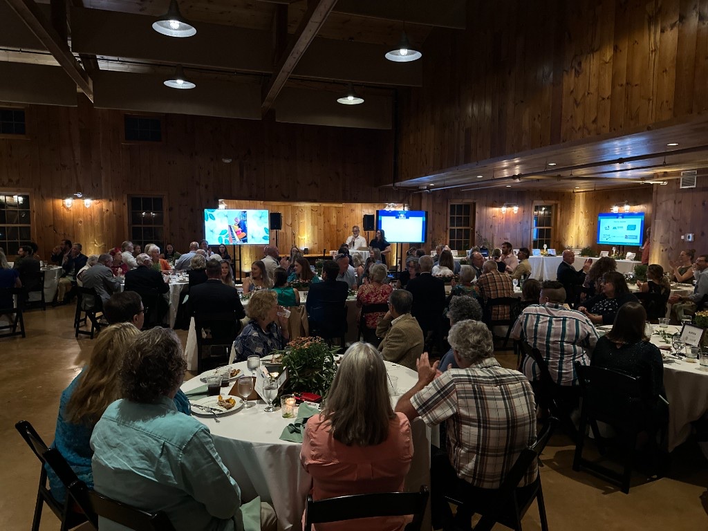 The Celebration Barn during the program, with three monitors around the room.