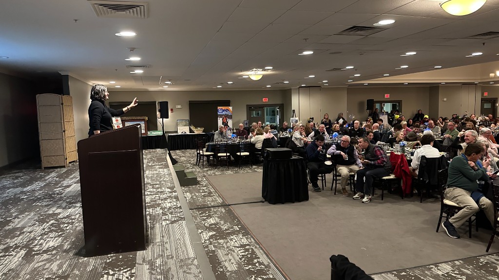 A speaker at the podium during Winterfest, with the room full.